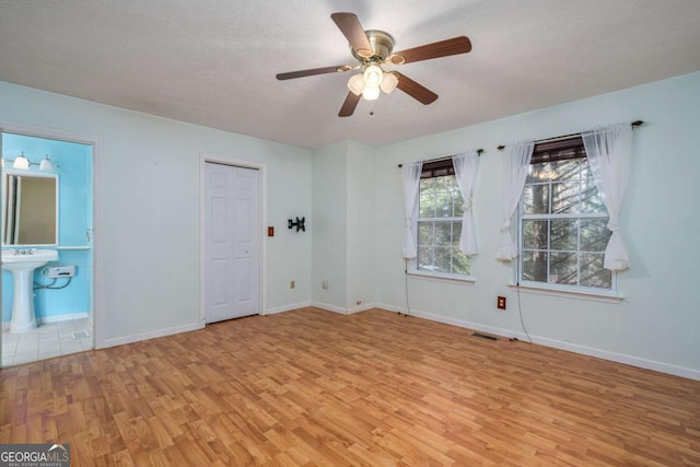 empty room with ceiling fan, sink, light hardwood / wood-style floors, and a textured ceiling