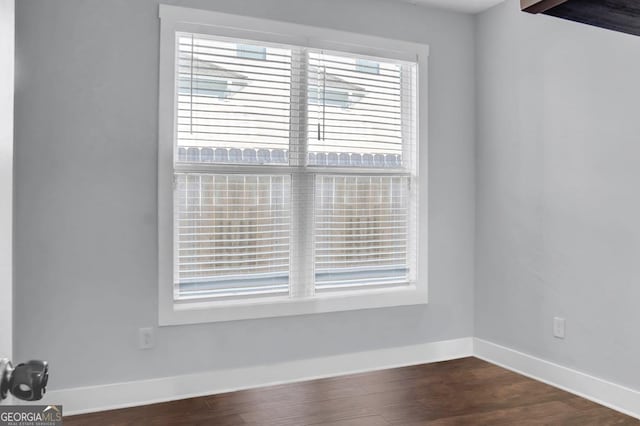 spare room with plenty of natural light and dark wood-type flooring