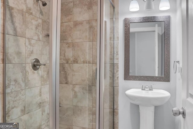 bathroom with a shower with door and sink