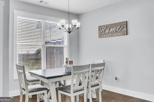 dining space with dark hardwood / wood-style floors and a notable chandelier