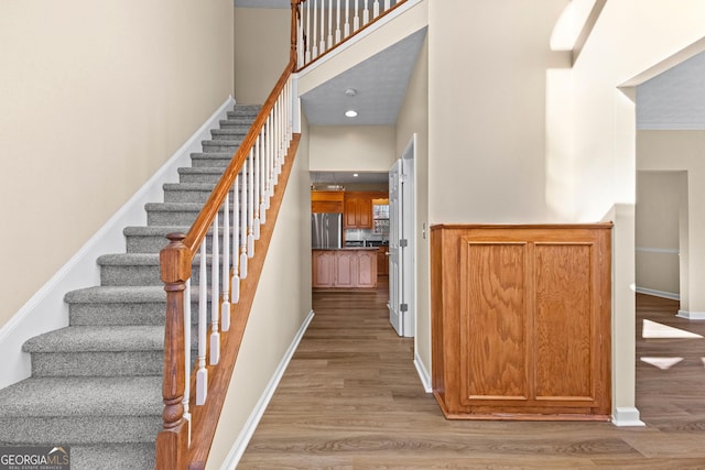 stairway with a towering ceiling and hardwood / wood-style flooring