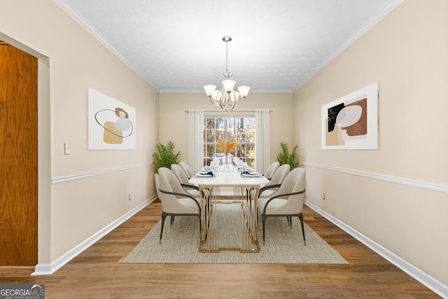 dining space featuring ornamental molding, an inviting chandelier, a textured ceiling, and hardwood / wood-style flooring