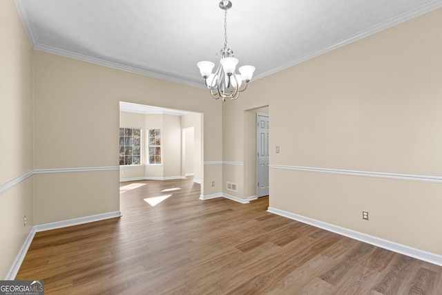 unfurnished room with a chandelier, ornamental molding, and hardwood / wood-style floors