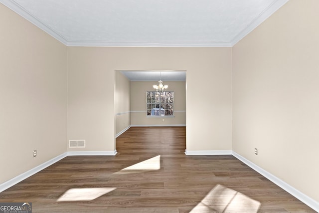 spare room featuring a notable chandelier, dark hardwood / wood-style flooring, and crown molding