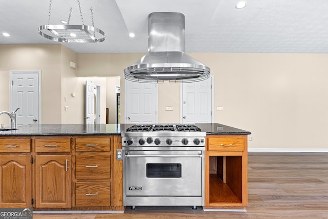 kitchen with dark stone countertops, sink, hardwood / wood-style flooring, island range hood, and luxury range