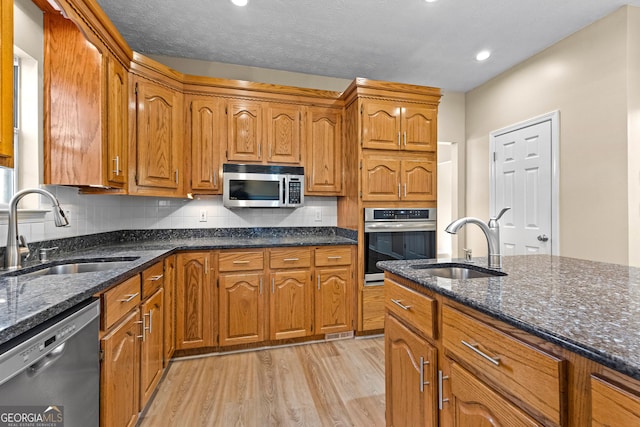 kitchen with light wood-type flooring, stainless steel appliances, tasteful backsplash, and sink