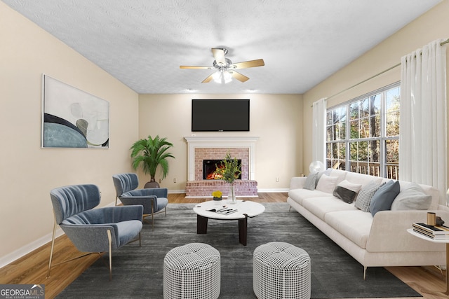 living room featuring ceiling fan, dark hardwood / wood-style flooring, a fireplace, and a textured ceiling