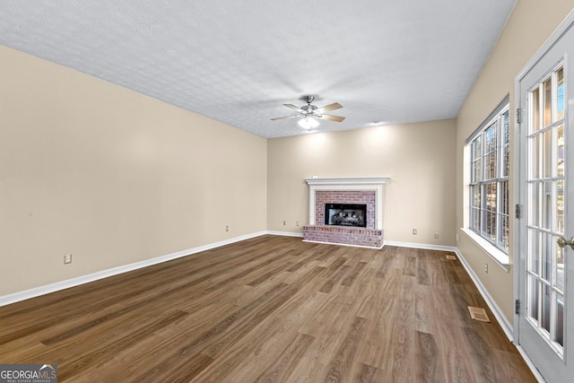 unfurnished living room featuring hardwood / wood-style flooring, a textured ceiling, ceiling fan, and a fireplace