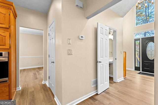 foyer entrance featuring a notable chandelier, a textured ceiling, and light hardwood / wood-style floors