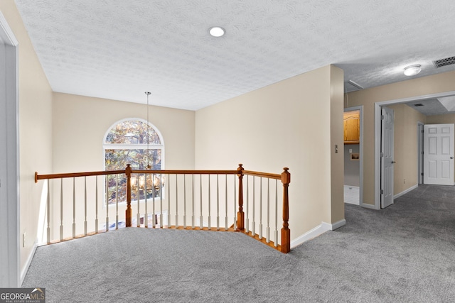 hall with a textured ceiling and carpet flooring