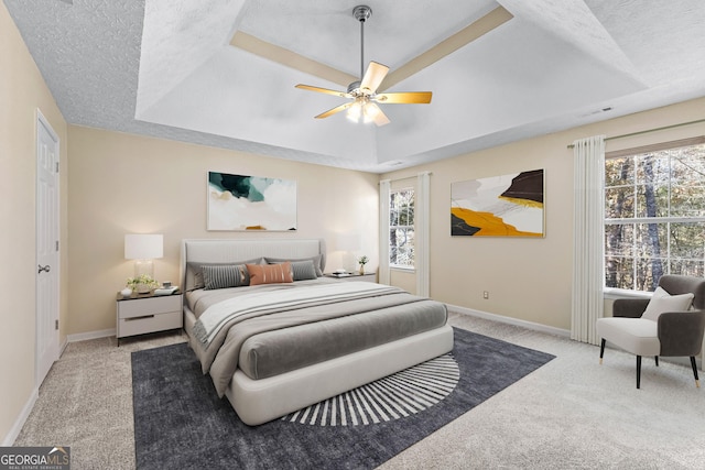 bedroom featuring ceiling fan, a tray ceiling, and a textured ceiling