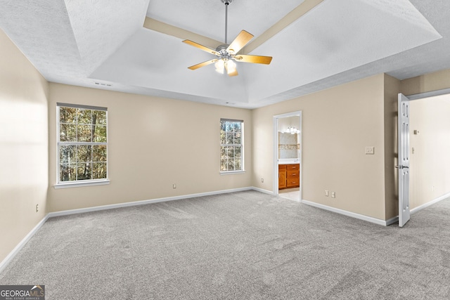 interior space featuring light carpet, ceiling fan, a raised ceiling, ensuite bath, and a textured ceiling