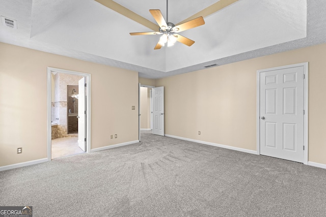 unfurnished bedroom with ceiling fan, connected bathroom, carpet, and a raised ceiling