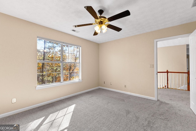 unfurnished room with a textured ceiling, ceiling fan, and carpet flooring