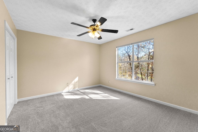 carpeted spare room featuring ceiling fan and a textured ceiling