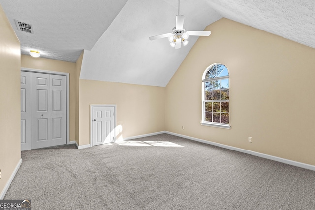 additional living space with carpet floors, a textured ceiling, lofted ceiling, and ceiling fan