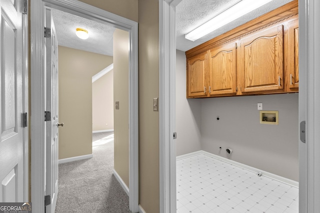 clothes washing area with cabinets, hookup for a gas dryer, a textured ceiling, and washer hookup