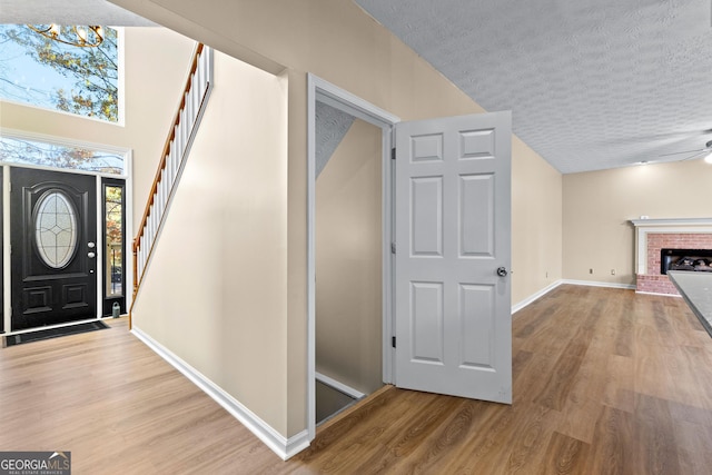 entrance foyer with a textured ceiling, a fireplace, and light hardwood / wood-style floors