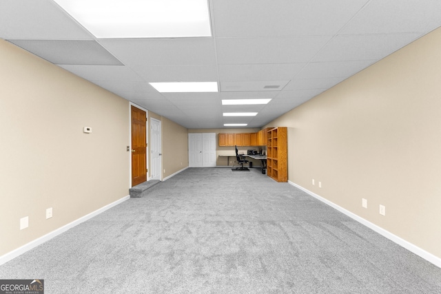 basement featuring light colored carpet and a drop ceiling