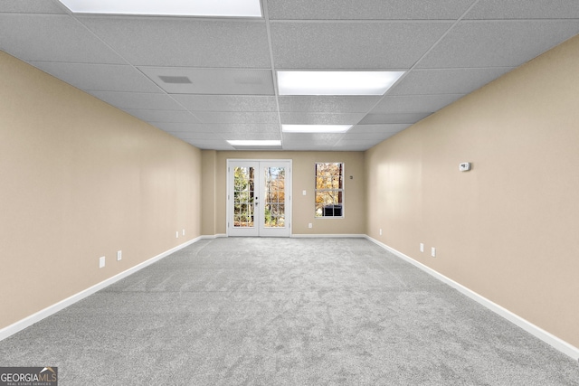 carpeted empty room with a drop ceiling and french doors