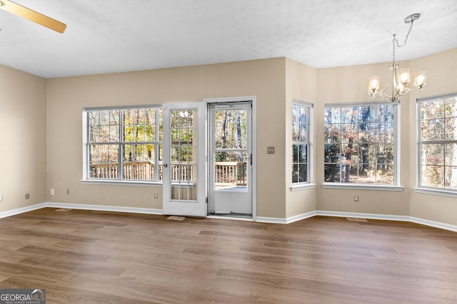 interior space featuring ceiling fan with notable chandelier, hardwood / wood-style floors, and a textured ceiling