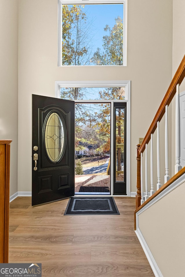 entrance foyer featuring light hardwood / wood-style floors and a towering ceiling