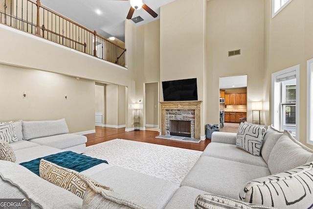 living room with a wealth of natural light, a stone fireplace, and a high ceiling