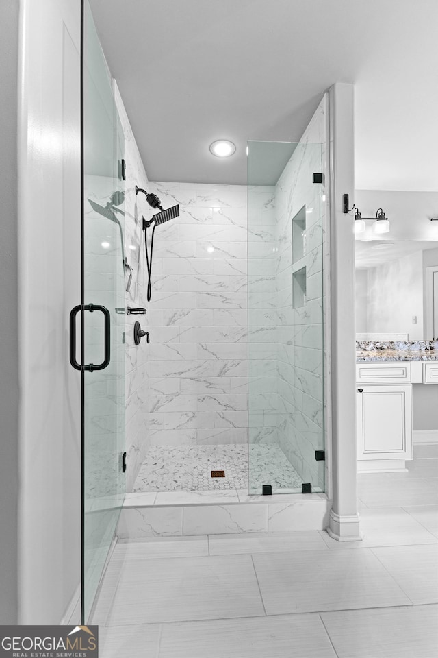 bathroom featuring tile patterned flooring, vanity, and a shower with shower door