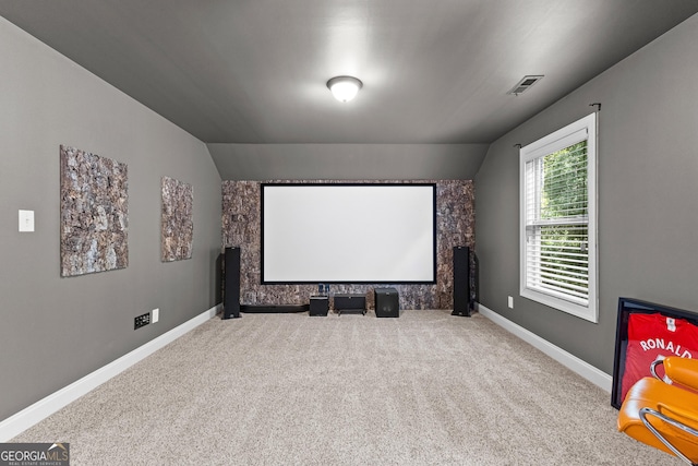 carpeted home theater featuring vaulted ceiling