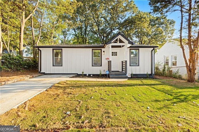 view of front of property with board and batten siding, a front yard, and fence