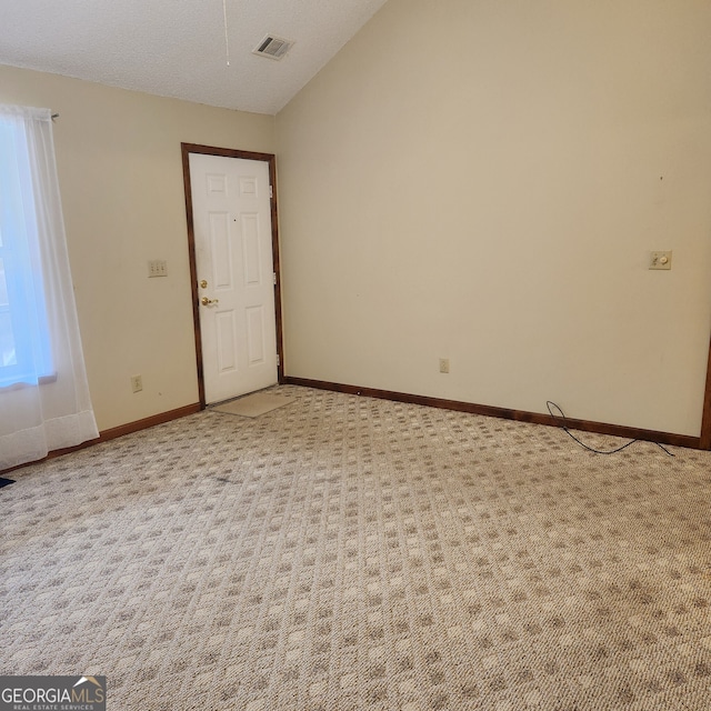 carpeted spare room featuring lofted ceiling and a textured ceiling