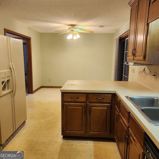 kitchen featuring white refrigerator with ice dispenser, a textured ceiling, kitchen peninsula, and light colored carpet