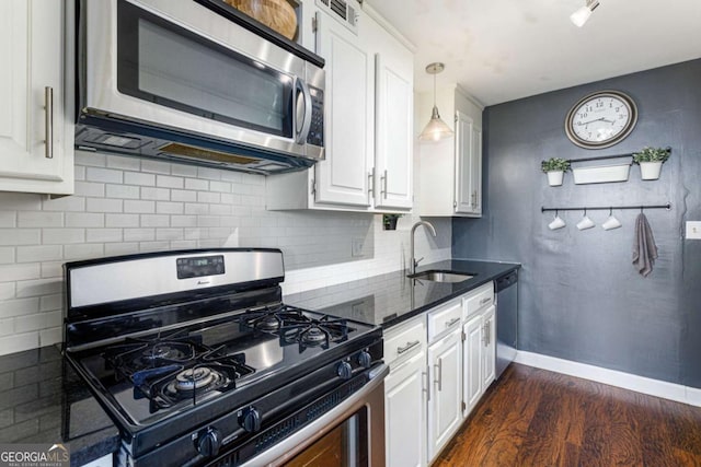 kitchen featuring appliances with stainless steel finishes, dark hardwood / wood-style flooring, sink, decorative light fixtures, and white cabinets