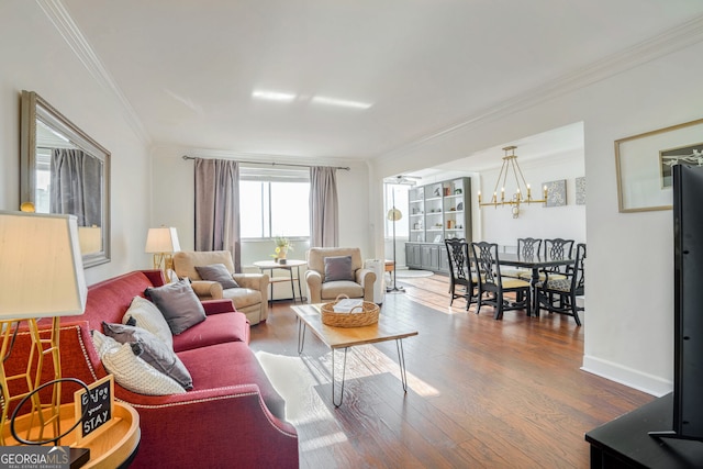 living room with wood-type flooring, ornamental molding, and an inviting chandelier