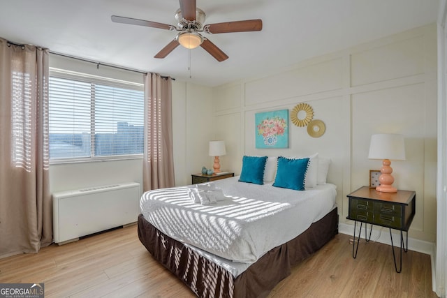 bedroom with ceiling fan, radiator heating unit, and light hardwood / wood-style floors