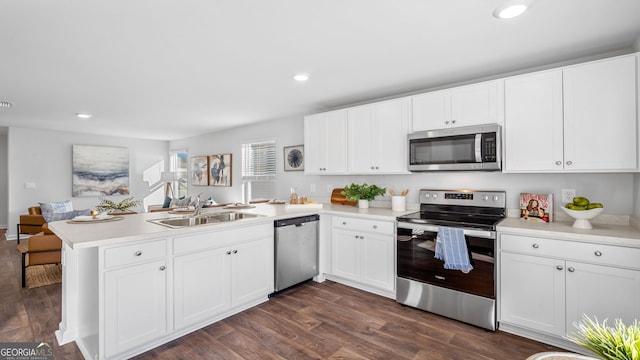 kitchen featuring sink, dark hardwood / wood-style flooring, kitchen peninsula, stainless steel appliances, and white cabinets