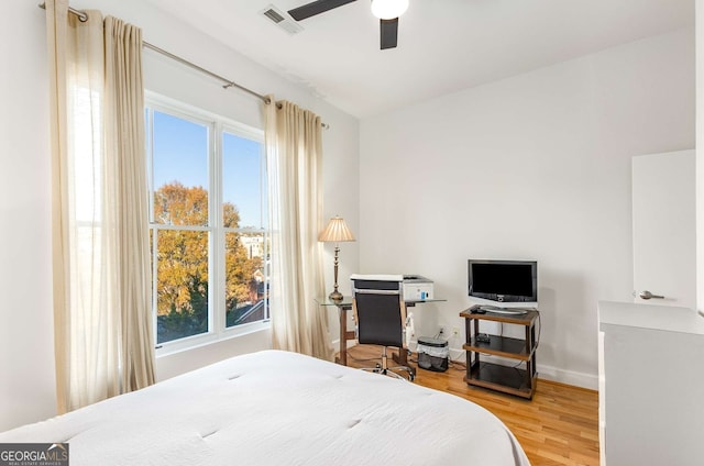 bedroom with hardwood / wood-style floors, ceiling fan, and multiple windows