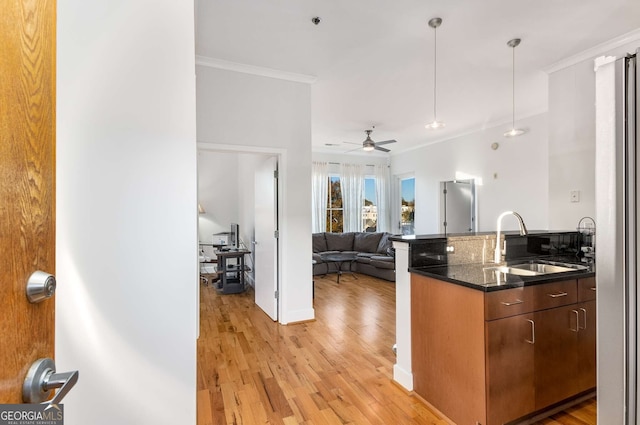 kitchen featuring ceiling fan, sink, light hardwood / wood-style floors, decorative light fixtures, and ornamental molding