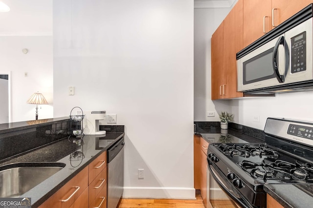 kitchen featuring appliances with stainless steel finishes, light hardwood / wood-style floors, and dark stone countertops