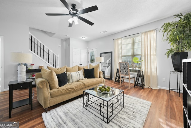 living room featuring wood-type flooring, a textured ceiling, and ceiling fan