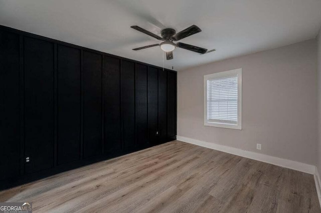 empty room with ceiling fan and light hardwood / wood-style flooring