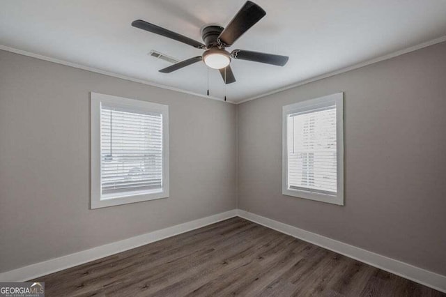 spare room featuring a wealth of natural light, dark hardwood / wood-style flooring, ceiling fan, and ornamental molding