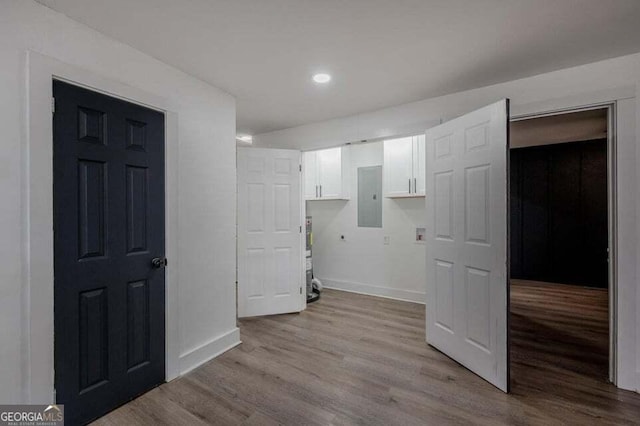 laundry room featuring cabinets, light wood-type flooring, and electric panel