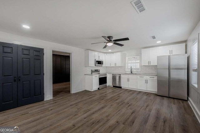 kitchen with white cabinetry, ceiling fan, dark wood-type flooring, backsplash, and appliances with stainless steel finishes