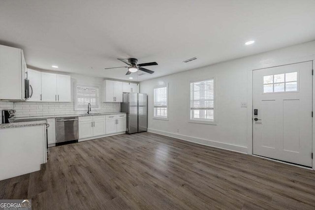 kitchen with backsplash, stainless steel appliances, dark wood-type flooring, sink, and white cabinetry