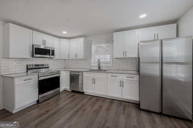 kitchen featuring backsplash, sink, appliances with stainless steel finishes, dark hardwood / wood-style flooring, and white cabinetry