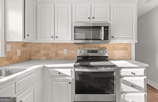 kitchen featuring decorative backsplash, white cabinetry, and appliances with stainless steel finishes