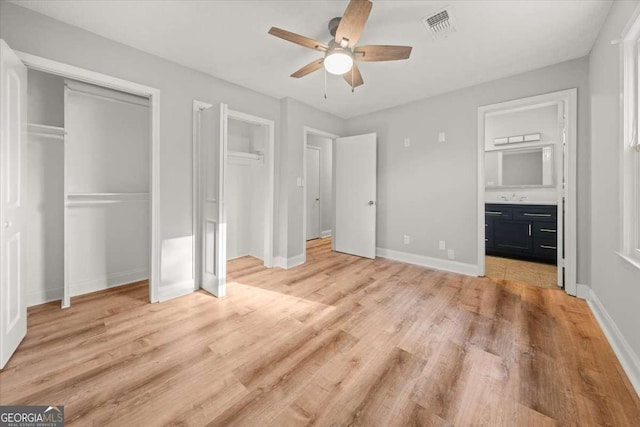 unfurnished bedroom featuring multiple closets, ceiling fan, and light hardwood / wood-style floors