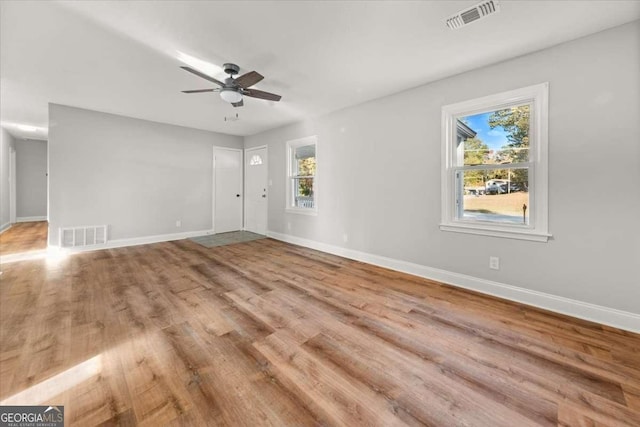 empty room with hardwood / wood-style floors, plenty of natural light, and ceiling fan