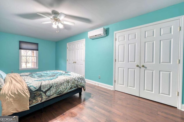 bedroom with ceiling fan, wood-type flooring, an AC wall unit, and two closets